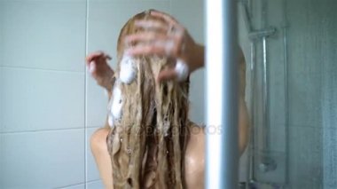 Duş alıyor ve saçları şampuanla yıkama genç ince kadın. Dolly kısa.
