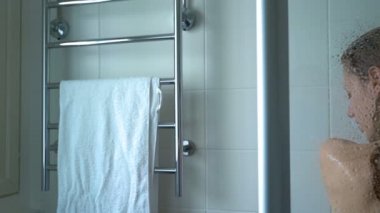 Duş alıyor ve onun saç yıkama genç ince kadın. Ağır çekim. Dolly atış.