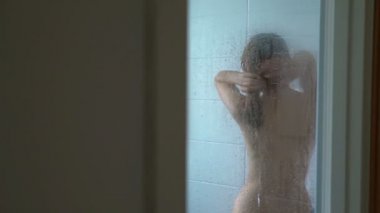 Duş alıyor ve onun saç yıkama genç ince kadın. Dolly atış. Ağır çekim