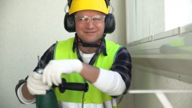Erkek inşaat işçisi matkap ile kameraya gülümseyen.