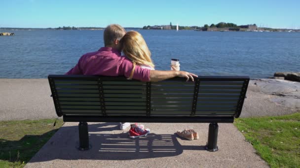 Pareja amorosa sentada en un banco junto al mar . — Vídeo de stock