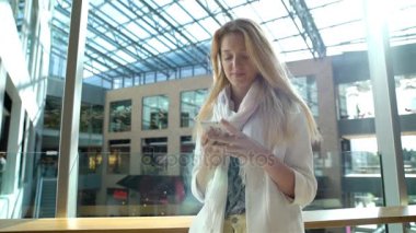 Genç ince kadın bir akıllı telefon ticaret ve office ortasında kullanır.