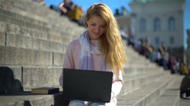 Genç kadın laptop bir kenara koyar ve merdivenlerden yavaş şehir merkezinde bir kitap alır
