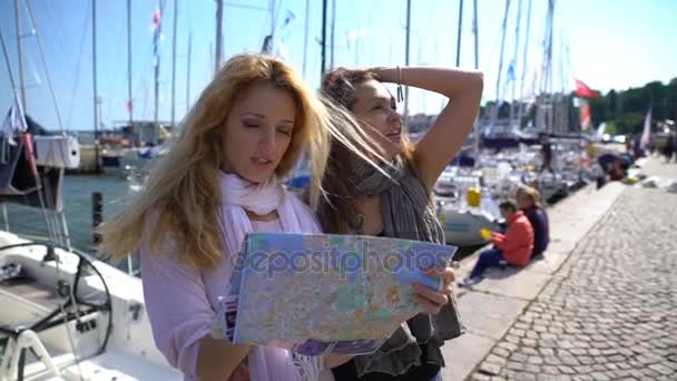 Два молодых путешественника руководствуясь бумажной картой на набережной города . — стоковое видео