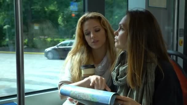 Два молодых путешественника едут на трамвае в незнакомый город и используют бумажную карту . — стоковое видео