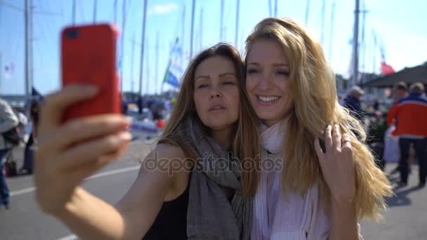 Dos encantadoras jóvenes haciendo selfies en el paseo marítimo. Moción lenta . — Vídeos de Stock