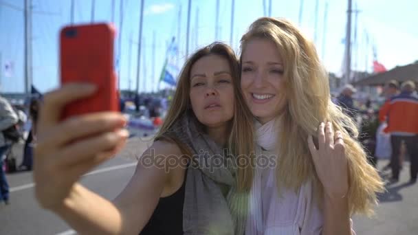 Two charming young women doing selfies on the promenade. Slow Motion. — Stock Video