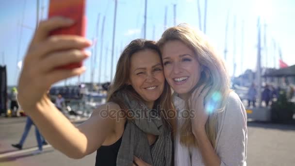 Dvě půvabné mladé ženy dělají selfie na promenádě. Zpomalený pohyb. — Stock video