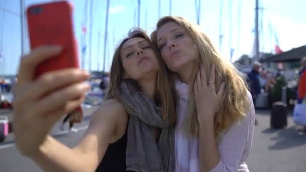 Zwei charmante junge Frauen machen Selfies auf der Promenade. Zeitlupe. — Stockvideo