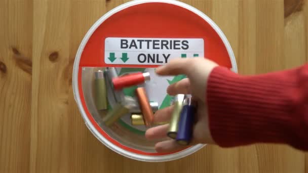 Viele Hände, die viele gebrauchte Batterien in die Recyclingbox legen. Ansicht von oben. — Stockvideo