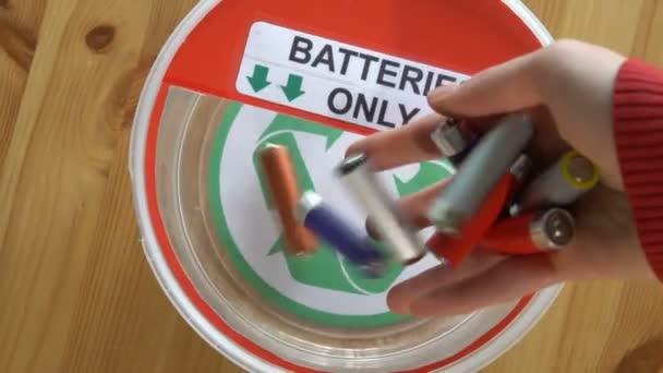 Many hands putting lot of used batteries in the recycling box. Top view. Slow motion — Stock Video