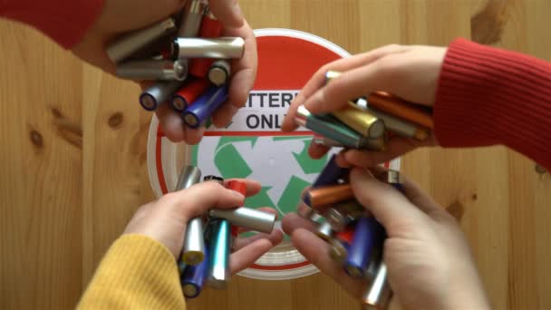 Muchas manos ponen muchas baterías usadas en la caja de reciclaje. Vista superior . — Vídeo de stock