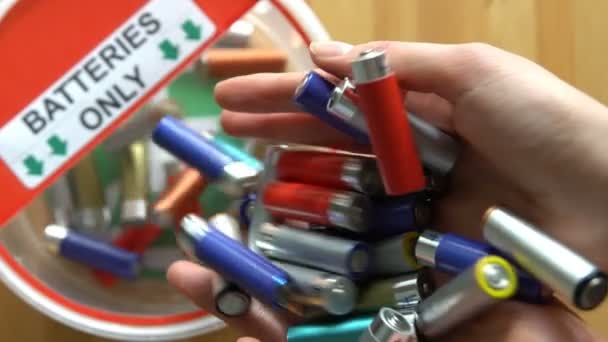 Mãos femininas colocando muitas baterias usadas na caixa de reciclagem. Vista superior. Movimento lento — Vídeo de Stock