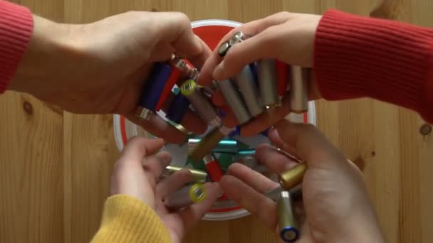 Viele Hände, die viele gebrauchte Batterien in die Recyclingbox legen. Ansicht von oben. Zeitlupe — Stockvideo