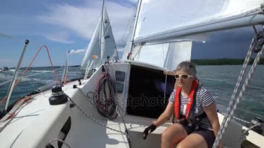 Bir kadın denizci yelken yükseltir ve denize.