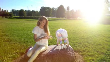 Genç anne ve kızı ile sabun köpüğü parkta oynarken.