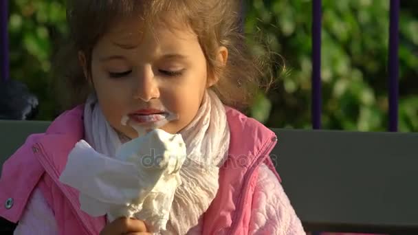 Menina bonito comendo sorvete no parque da cidade . — Vídeo de Stock