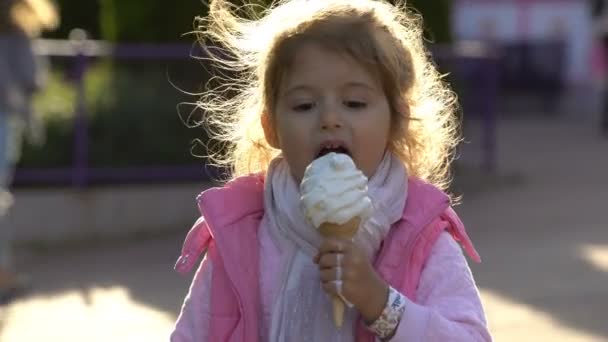 Menina bonito comendo sorvete no parque da cidade . — Vídeo de Stock