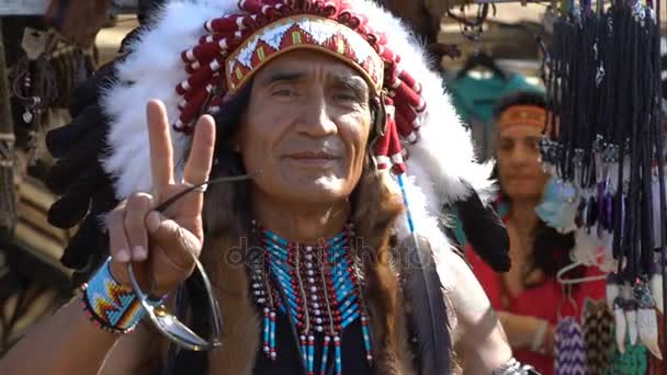 Людина одягнені як індіанці американських індіанців поруч з його магазин сувенірів. Повільний рух — стокове відео