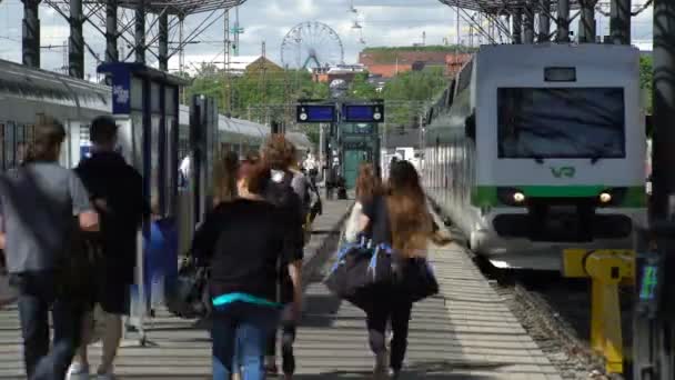 Многие пассажиры и поезда на железнодорожном вокзале в городе Хелли в Финляндии. Время покажет . — стоковое видео