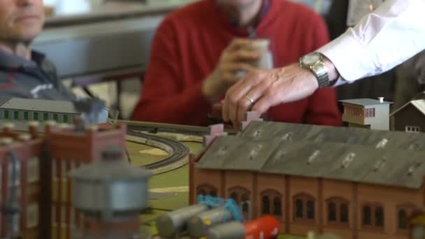 Пожилой человек управляет миниатюрными моделями поездов — стоковое видео