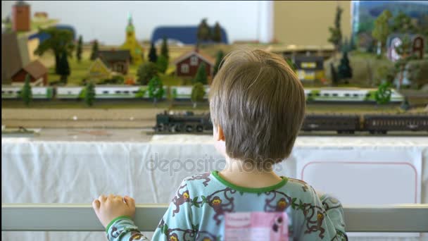 Kleiner Junge beobachtet perfekte Modelle von Zügen und Bahnhöfen. — Stockvideo