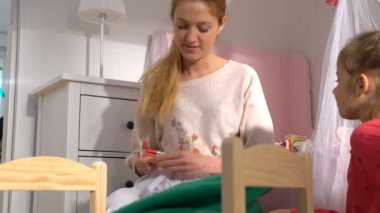 Oyuncaklar ve küçük kız onları geri dönüşüm kutusunu evde içine koyarak tüm pilleri çekici genç bir anne. Yerli ayıran atık. Sadece pil.