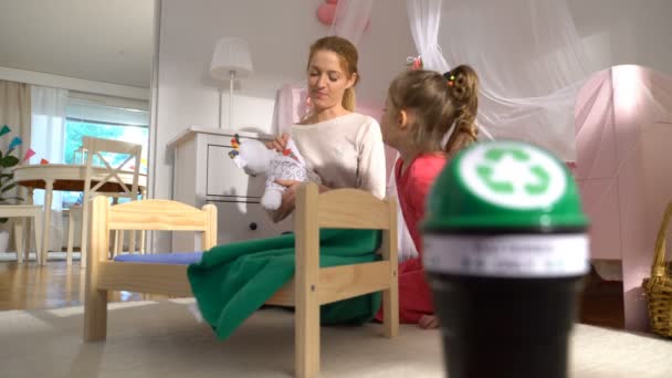 Mutter nimmt gebrauchte Batterien aus Spielzeug, Kind steckt sie in Recyclingbox. — Stockvideo