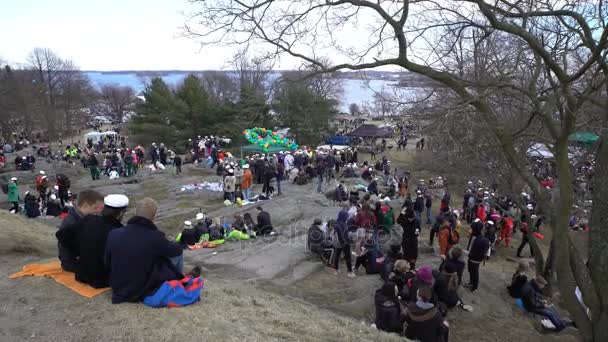 Многие счастливые студенты устраивают пикник, пьют, едят и веселятся в городском парке — стоковое видео