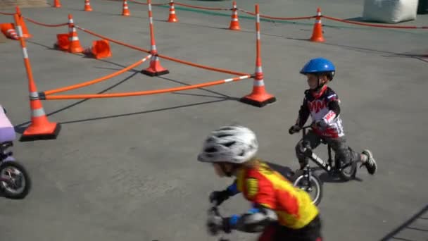 Pequeños corredores. Los niños montan bicicletas en destilación en un parque de la ciudad . — Vídeo de stock