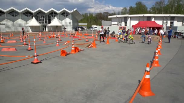 Pequeños corredores. Los niños montan bicicletas en destilación en un parque de la ciudad . — Vídeos de Stock