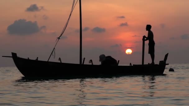 Dois pescadores lavam o velho barco ao pôr-do-sol no Oceano Índico. Movimento lento — Vídeo de Stock