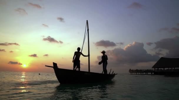 Deux pêcheurs lavent un vieux bateau au coucher du soleil dans l'océan Indien. Mouvement lent — Video