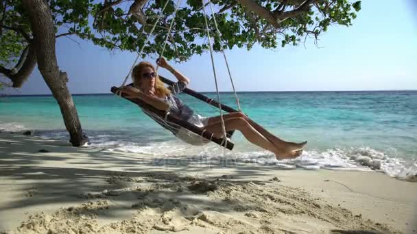 Jonge vrouw genieten van een rust in een hangmat op het tropische strand. — Stockvideo