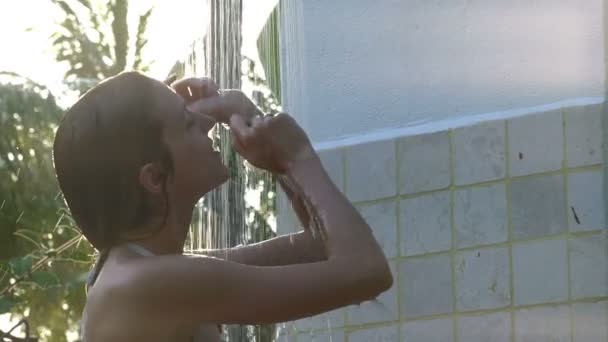 Молода жінка насолоджується освіжаючим душем у тропічному саду. Повільний рух — стокове відео