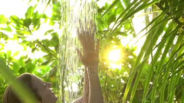 Joven mujer delgada disfrutando de una refrescante ducha en un jardín tropical. Movimiento lento . — Vídeos de Stock