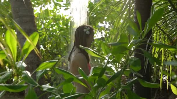 Joven mujer delgada disfrutando de una refrescante ducha en el jardín tropical . — Vídeo de stock