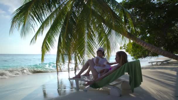 En ung mamma och hennes lilla dotter njuta av semester på en tropisk strand. — Stockvideo