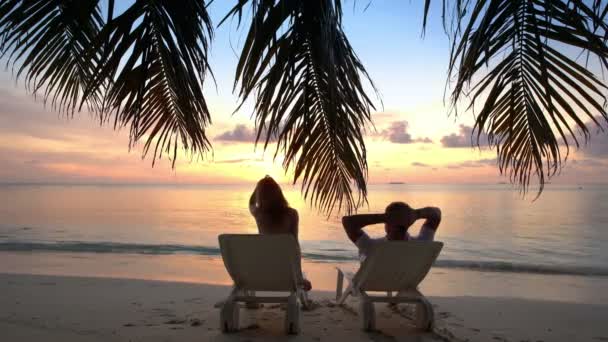 Ζευγάρι σε μια τροπική παραλία θαυμάζοντας το ηλιοβασίλεμα. — Αρχείο Βίντεο
