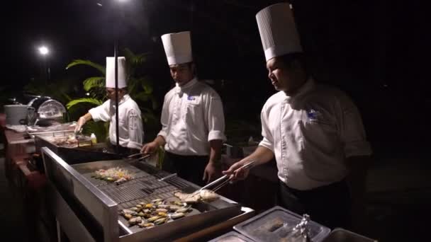 Les chefs préparent les palourdes et les poissons dans un restaurant en plein air le soir . — Video