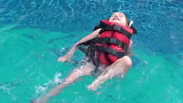 Kleines Mädchen in Schwimmweste schwimmt im Pool. — Stockvideo