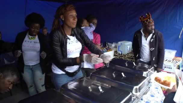 Cheerful street cooks from Cameroon offer passers-by dishes of African cuisine. They sing and dance. — Stock Video