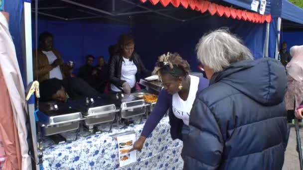 Cheerful street cooks from Cameroon offer passers-by dishes of African cuisine. They sing and dance. — Stock Video