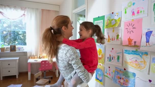 Malá holčička a její matka hraní ve školce proti zdi s dětské kresby — Stock video