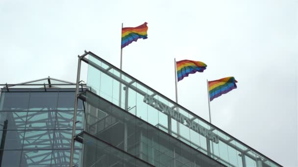 Regenbogenfahnen zur Unterstützung der Gleichberechtigung auf dem Dach eines Wolkenkratzers in der Innenstadt. — Stockvideo