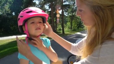 Anne koyar güvenlik kask üzerinde küçük kızları başıdır