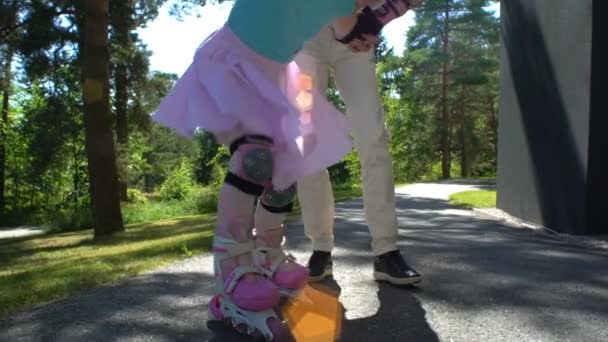 Los padres ayudan a su hijita a patinar en patines — Vídeos de Stock