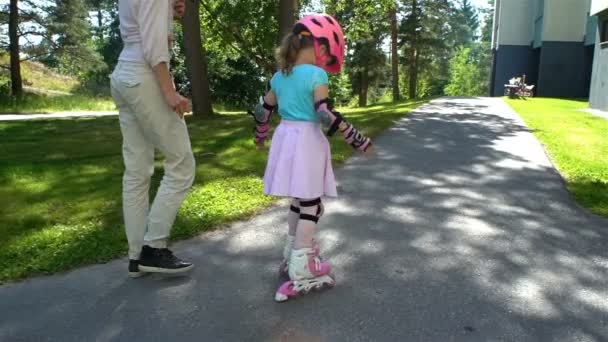 Mamá ayuda a su hijita a patinar en patines — Vídeos de Stock