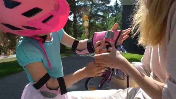 어머니는 그녀의 딸 보호 팔꿈치 패드를 착용 하 고 장갑을 하는 데 도움이 — 비디오