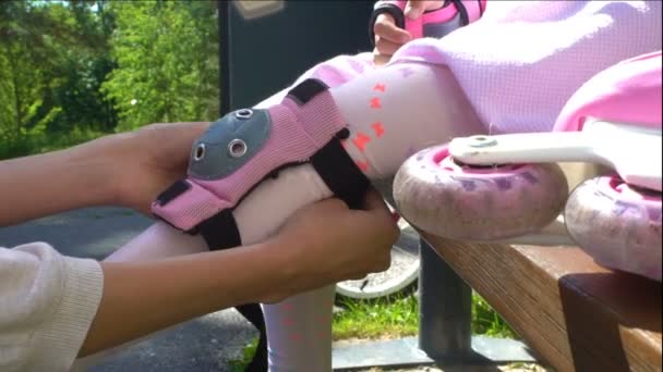 Mère aide sa fille à porter des genouillères protectrices — Video